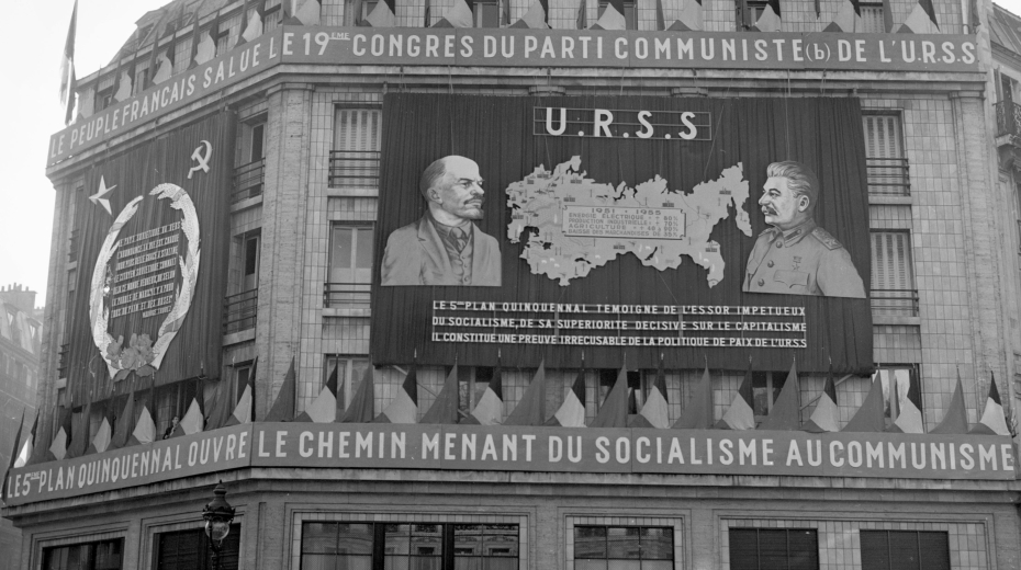 Sídlo Francouzské komunistické strany v Paříži v roce 1952, vyzdobené nápisy jako „Francouzský lid vítá 19. sjezd Komunistické strany SSSR“ nebo „5. pětiletý plán otevírá cestu od socialismu ke komunismu“. Zdroj: Public Domain 