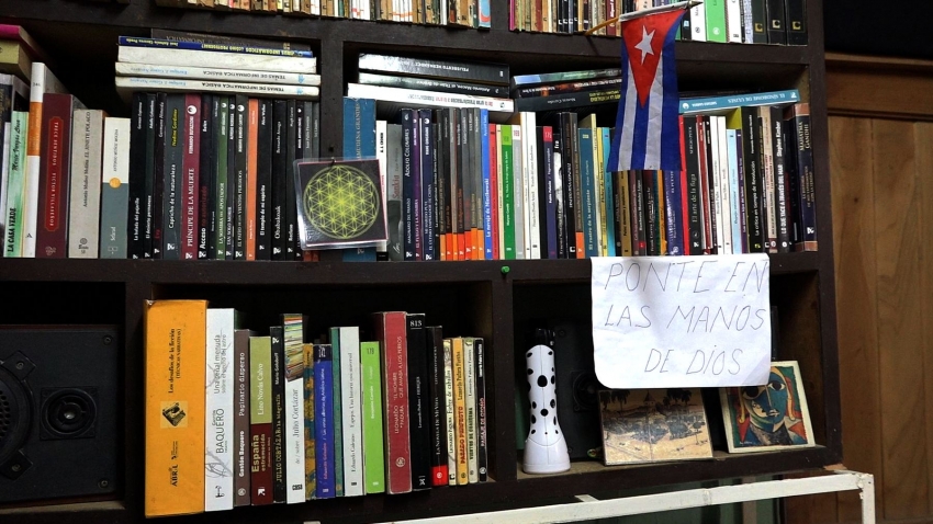 Quiñonesova knihovna s kubánskou vlajkou a nápisem Vlož sebe sama do rukou božích. Zdroj: Post Bellum