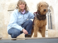 Eva Vorlíčková spolu s pejskem. V pozadí gotický loukovský kostelík sv. Markéty, o který se stará spolek podlipnických kostelů, ve kterém paní Eva už dlouhá léta aktivně působí. 