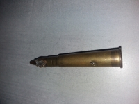 Kulometná patrona, ve které je zaryta střepina z granátu. Josef Olšaník ji měl v zásobách střeliva v kapse kabátu, a zachránila mu tak život při bojích u Dunkerque