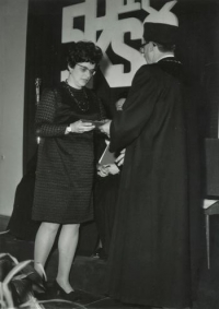 Promoce, Iva Ondráčková přebírá svůj červený diplom –  (na oponě za ní je velký nápis „50 let KSČ“), Brno, léto 1971