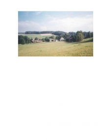 Pohled na místo, kde dříve stával statek rodiny Hrdinových. Vlevo skladovací hala JZD, vpravo vejminek a v popředí stodola
