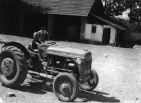 The courtyard on the farm of the Cecha family in Nezdenice. There is a Ferguson tractor (imported by UNRA) in the front. Oldřich, the oldest grandson, son of the oldest daughter Miloslava, is sitting on the tractor. In the background there is František Cecha, a machine shed and a chicken coop. Photo taken around 1949.