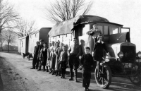 Strýc Mileny Ručkové Rudolf Kutač (v károvaném svetru a rajtkách) s rodinou na štaci s kolotočem a střelnicí / asi 40. léta