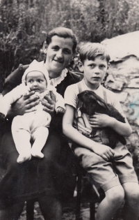 Opatrovnice Hedvika Vařbuchtová chová na klíně Gertrudu a vedle sedí Gertrudy nevlastní bratr Stanislav, 1944