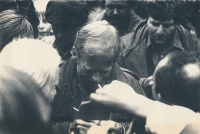 Obzvláště vyvedený snímek, na němž je zachycen Václav Havel ve chvíli, kdy v záplavě návštěvníků Folkové Lipnice rozdává autogramy a současně mu přes rameno nahlíží zaražený Viktor Púčala, příslušník okresní StB, září 1988