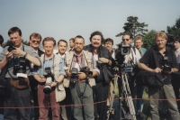 Pamětník uprostřed fotoreportérů, v tmavém saku s knírem, 90. léta