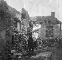 Paní Plachká před vyhořelým doškovým domem ve Štítině v roce 1945