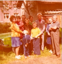 Pamětník v šedivém obleku uprostřed na rodinné fotografii na počátku 70. let