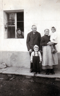 Monika Ruská s dědou Františkem Theuerem, mladší sestrou, sousedkou a matkou (v okně) na statku v Bolaticích, kolem roku 1949