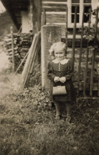 Anna Feigl jako malá ve svátečním oblečení s kabelkou před rodným domem č.p. 1 v Bučnici (nyní č.p. 190)