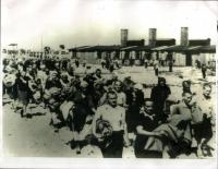 podzim 1944, Birkenau - Osvětim, Markéta Nováková jde v průvodu, je uprostřed a hledí před sebe na výrazného muže v popředí, za ní se směje její sestřenice Ilsa Maier s dekami