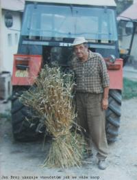 Jan Broj s traktorem ukazuje vnoučatům jak se váže snop