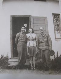 Američtí vojáci s pamětníkovou sestrou Boženou a prodavačkou Marií Koutníkovou před domem v Hluboké, 1945