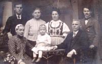 Rodinná fotografie: horní řada první zleva otcův bratr (oko), uprostřed v kroji maminka Růžena Měkynová, první řada sedící zprava tatínek Josef Měkyna (s ježkem), holčička sedící na stolku – sestra Evy Hefer Hana Měkynová-Latošinská (1920)