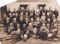 1930 - Matěj Komosný na fotografii z první třídy. Fotografie je bohužel poškozená vnuky. Pamětník je uprostřed s nejvíc poškrábaným obličejem.