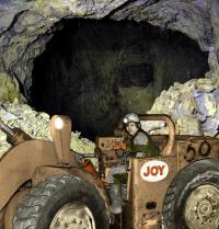 Josef Šmoldas řídí kolový nakladač JOY TLF 4 / pohled do dobývky v prvním patře dolu ve Zlatých Horách / kolorovaná fotografie / 1981