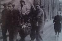 Mojmír Petráň (v brýlích) pomáhá odnášet těžce raněného - při Pražském povstání 5. 5. 1945; na Husově třídě na Žižkově